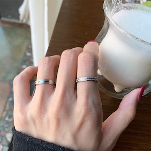 Peut inclure: Une tasse en céramique blanche avec une anse noire et le texte "But First, Coffee" en noir, en gras. La tasse est posée sur une surface blanche.