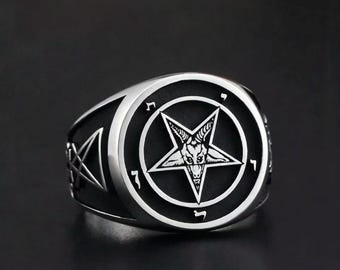 Op de afbeelding: Zilverkleurige ring met een zwarte achtergrond. De ring heeft een prominent pentagramontwerp met een geitenkop in het midden. De ring heeft een dikke band en een gedetailleerd, getextureerd oppervlak.