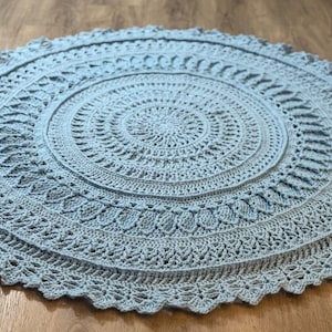 Puede incluir: Un letrero de madera rústico blanco con la palabra "Welcome" escrita a mano. El letrero tiene un aspecto envejecido y un elemento floral decorativo. El fondo es una textura de madera borrosa.