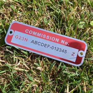 May include: Red metal tag with white lettering that reads "Commission No. G23N ABCDEF-012345 Z".