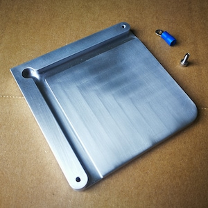 May include: A silver metal plate with a rectangular shape and a raised edge. The plate has two holes on the bottom and one hole on the top.