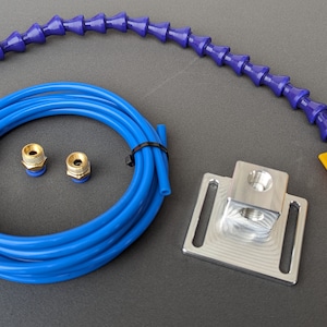Może przedstawiać: Niebieski wąż powietrzny z dwoma mosiężnymi złączami, elastyczny fioletowy wąż powietrzny z żółtą dyszą i srebrny metalowy uchwyt montażowy.