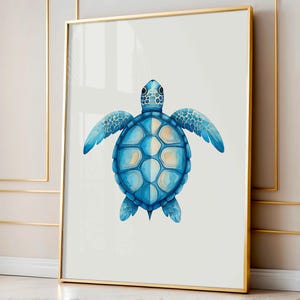 May include: A framed watercolor print of a sea turtle. The turtle is depicted in shades of blue with a light yellow and white shell. The artwork is framed in a gold-colored metal frame and hangs on a white wall.