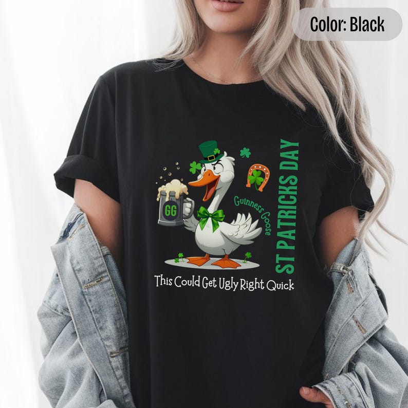 A black t-shirt featuring a cartoon goose dressed for St. Patricks Day with a green bow tie, leprechaun hat, and shamrocks. The goose, named Guinness Goose, holds a frothy beer mug labeled GG with a playful, mischievous expression. Surrounding elements include a horseshoe and festive decorations. The words ST PATRICKS DAY are written vertically on the right, with the words This Could Get Ugly Right Quick is written horizontally below.