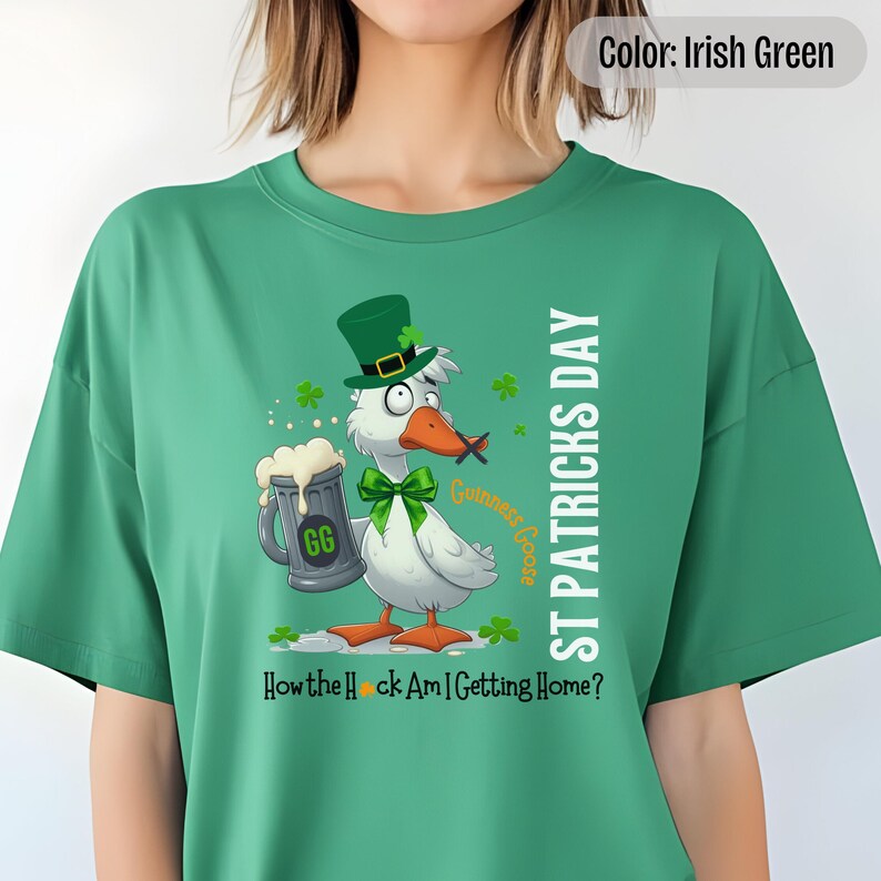 An irish green t-shirt featuring a cartoon goose dressed for St. Patricks Day with a green bow tie, leprechaun hat, and shamrocks. The goose, named Guinness Goose, holds a frothy beer mug labeled GG with a playful, mischievous expression. Surrounding elements include shamrocks. The words ST PATRICKS DAY are written vertically on the right, with the words How the Heck Am I Getting Home? are written horizontally below.