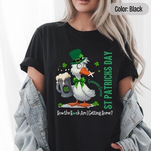 A black t-shirt featuring a cartoon goose dressed for St. Patricks Day with a green bow tie, leprechaun hat, and shamrocks. The goose, named Guinness Goose, holds a frothy beer mug labeled GG with a playful, mischievous expression. Surrounding elements include shamrocks. The words ST PATRICKS DAY are written vertically on the right, with the words How the Heck Am I Getting Home? are written horizontally below.