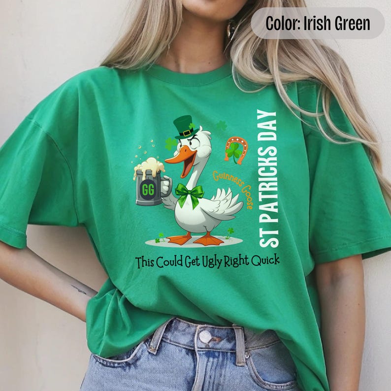 An irish green t-shirt featuring a cartoon goose dressed for St. Patricks Day with a green bow tie, leprechaun hat, and shamrocks. The goose, named Guinness Goose, holds a frothy beer mug labeled GG with a playful, mischievous expression. Surrounding elements include a horseshoe and festive decorations. The words ST PATRICKS DAY are written vertically on the right, with the words This Could Get Ugly Right Quick is written horizontally below.