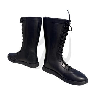 Puede incluir: Un par de botas negras de cuero con cordones y ca&ntilde;a alta. Las botas tienen una puntera redonda y una suela gruesa.