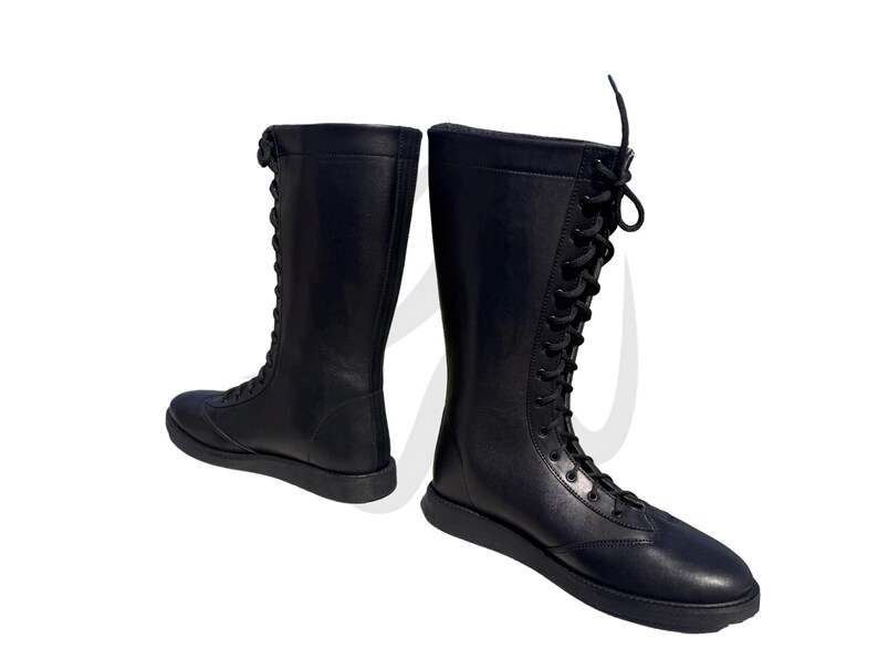Puede incluir: Un par de botas negras de cuero con cordones y ca&ntilde;a alta. Las botas tienen una puntera redonda y una suela gruesa.