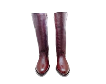 May include: A pair of brown leather knee-high boots with a pointed toe.