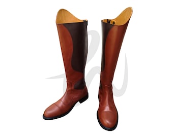 Könnte beinhalten: Ein Paar braune Reitstiefel aus Leder mit einem kontrastierenden dunkelbraunen Einsatz an der Seite. Die Stiefel haben eine spitze Zehenpartie und einen hohen Schaft.