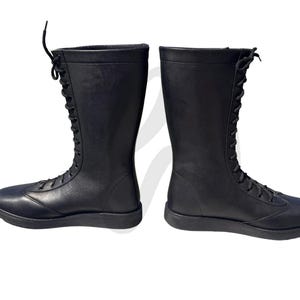 Puede incluir: Un par de botas de lucha libre de cuero negro con cordones en la parte delantera. Las botas tienen una suela plana.