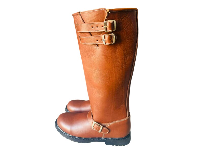 May include: Brown leather knee-high boots with two buckles on the shaft and one buckle on the ankle.