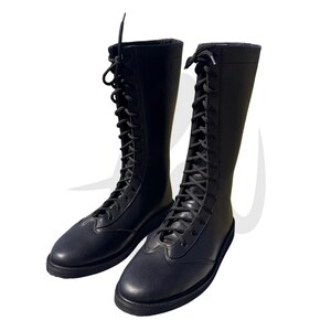 Puede incluir: Un par de botas de lucha libre de cuero negro con cordones. Las botas tienen una ca&ntilde;a alta y una suela gruesa.