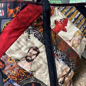 Könnte beinhalten: Eine Patchwork-Tragetasche mit schwarzem Griff und Besatz. Die Tasche zeigt verschiedene Stoffmuster, darunter Bilder von Männern, Hydranten und abstrakten Designs in Rot, Schwarz und Beige. Die Tasche ist aus gestepptem Stoff gefertigt.