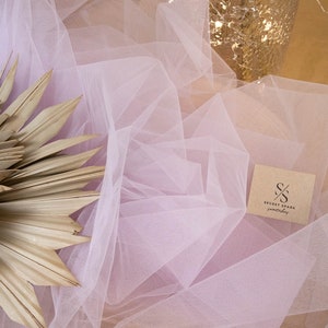 May include: A pale pink tulle fabric with a brown paper tag that says "SECRET SPARK fabrics".