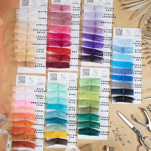 May include: A color chart of sheer organza fabric swatches in a variety of colors, including white, ivory, vanilla, sun-kissed beige, creamy peach, champagne, light gold, golden, tan, brown, plum rose, dark mauve, rose mauve, lipstick, fuchsia, magenta, red, cranberry, burgundy, silver gray, purple lavender, amethyst, lilac blush, ultra violet, royal purple, deep purple, black berry, soft powder blue, dusk blue, summer sky, turquoise blue, steel blue, royal blue, dark gray, navy, black, aqua marine, mint, jade blue, teal blue, seafoam blue, deep teal, sage, yellow sun, brown, green apple, leaf green, avocado, moss green, olive, forest green, emerald, hunter green, and rust. The chart is labeled "Glimmer: Airy & Sheer Crystal Effect Organza".