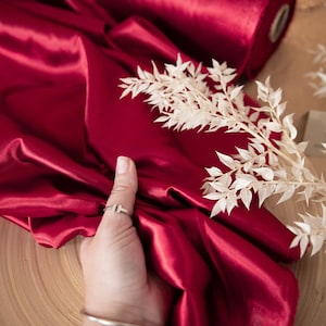 May include: A roll of deep red satin fabric with a white label that says "SECRET SPARK fabrics".