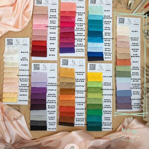 May include: A color chart of 96% polyester and 4% spandex satin fabric swatches in various colors. The fabric is described as "soft & silky satin fabric with a slight stretch." The chart includes a variety of colors, including white, black, red, blue, green, and yellow. The chart also includes the text "Iconic" and "New Trendy Hues."