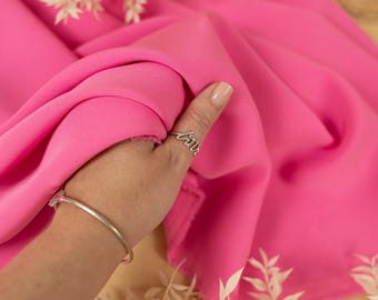 May include: A close-up of a bright pink fabric, showing its texture and drape. The fabric is held in a hand, with a ring on the finger. The text "SECRET SPARK" is visible in the top left corner of the image.