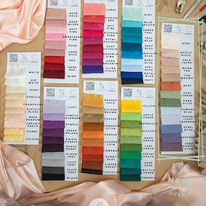 Puede incluir: Una carta de colores de muestras de tela de sat&eacute;n 96% poli&eacute;ster y 4% elastano en varios colores. La tela se describe como "tela de sat&eacute;n suave y sedosa con un ligero estiramiento". La carta incluye una variedad de colores, incluyendo blanco, negro, rojo, azul, verde y amarillo. La carta tambi&eacute;n incluye el texto "Iconic" y "New Trendy Hues."