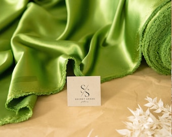 May include: A roll of bright green satin fabric with a white tag that says "Secret Spark Fabrics" on a brown paper background.
