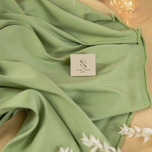 May include: A sage green fabric swatch with a small brown paper tag that says "Secret Spark Fabrics".
