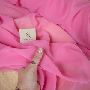 May include: Pink sheer fabric with a small brown tag that says "SECRET SPARK fabrics".