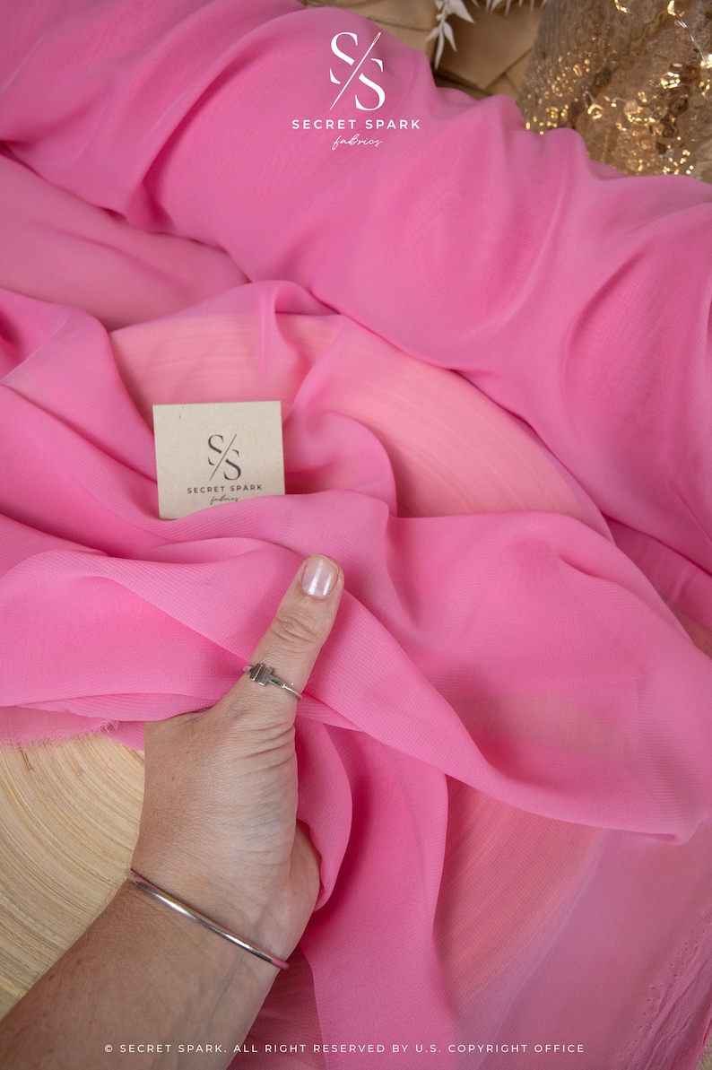 May include: Pink sheer fabric with a small brown tag that says "SECRET SPARK fabrics".