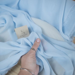 Pode incluir: Um tecido transparente azul claro com um r&oacute;tulo branco que diz "SECRET SPARK fabrics".