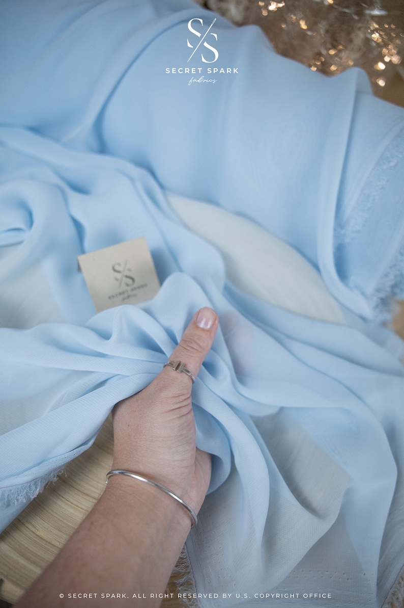 Pode incluir: Um tecido transparente azul claro com um r&oacute;tulo branco que diz "SECRET SPARK fabrics".