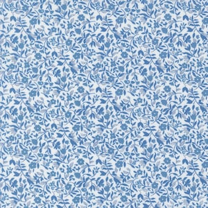 May include: A close-up of a fabric with a repeating floral pattern. The design features small blue flowers and leaves on a white background. The pattern is dense and covers the entire surface, creating a textured appearance.