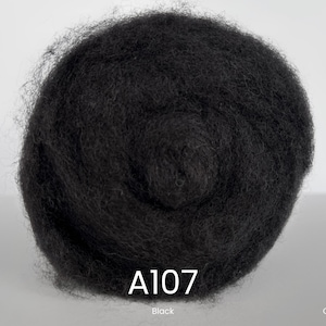 Könnte beinhalten: Nahaufnahme einer Kugel aus schwarzer Kardwolle. Das Bild enthält den Text "A107" in Weiß, darunter "Black". Die Wörter "ANNA FELT" und "Carded Wool" sind ebenfalls zu sehen.