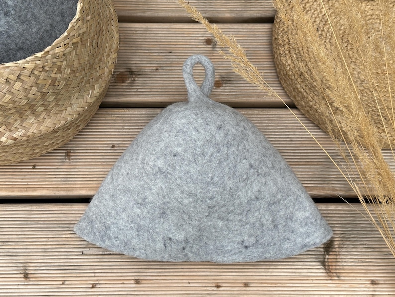 K&ouml;nnte beinhalten: Ein grauer Filzhut mit einem Schlaufe. Der Hut liegt auf einer Holzoberfl&auml;che.