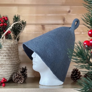 Può includere: Un cappello di feltro grigio con una corona a punta e un anello in cima. Il cappello è su una testa di manichino bianca.