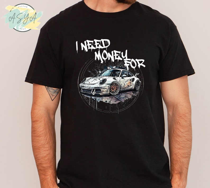 May include: Black t-shirt featuring a white sports car graphic and the text "I NEED MONEY FOR" in a graffiti style.