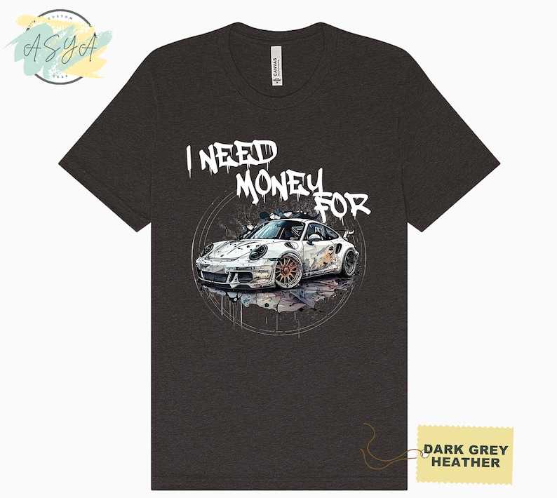 May include: Dark grey heather t-shirt featuring a white sports car graphic and the text "I NEED MONEY FOR" in white graffiti-style lettering.