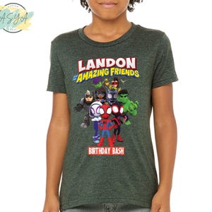 Pode incluir: Camiseta verde com um gr&aacute;fico de super-her&oacute;is de desenhos animados e o texto "Landon's Amazing Friends Birthday Bash".