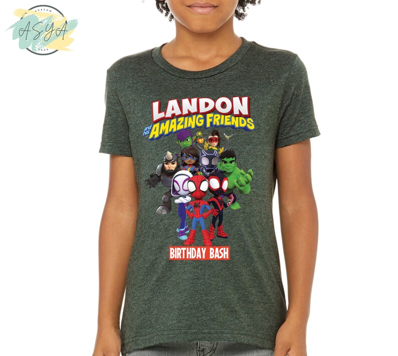 Pode incluir: Camiseta verde com um gr&aacute;fico de super-her&oacute;is de desenhos animados e o texto "Landon's Amazing Friends Birthday Bash".