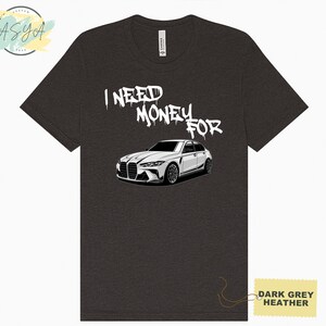 May include: Dark grey heather t-shirt with a white car and the text "I need money for" in white spray paint font.