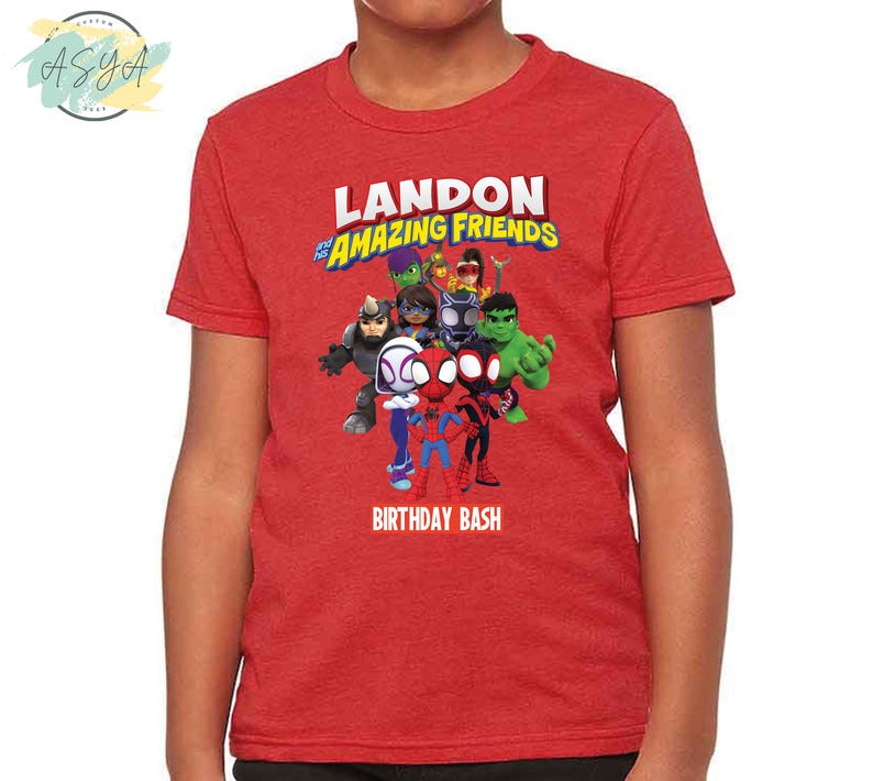 Pode incluir: Camiseta vermelha com um gr&aacute;fico de super-her&oacute;is de desenhos animados e o texto "Landon's Amazing Friends Birthday Bash".