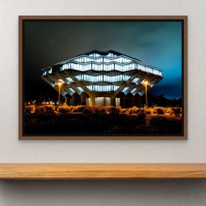 May include: A night time photograph of a modern, concrete building with a unique, geometric design. The building is lit up with bright white lights, and the surrounding area is dark. The building is surrounded by trees and bushes.