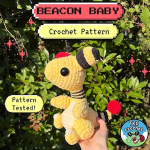 May include: A yellow crocheted plush toy with a red head patch, black and yellow striped ears, a black and yellow striped neck, and a red tail tip. The image includes text reading BEACON BABY, Crochet Pattern, Pattern Tested!, and TKO crochet.