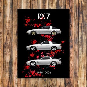 Op de afbeelding: Een zwarte poster met drie witte RX-7 auto's met gouden wielen, tegen een zwarte achtergrond. Rode bloemmotieven omringen de auto's. De tekst "RX-7" staat bovenaan en "1978-2002" onderaan.