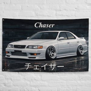 May include: White car poster with the word "Chaser" in a stylized font above the car. The Japanese word for "Chaser" is below the car. The car is white and has custom rims.