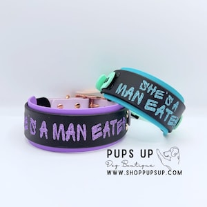 May include: Two dog collars with black bands and metallic hardware. One collar has a purple interior and purple glitter text reading SHE'S A MAN EATER. The other has a teal interior and teal glitter text reading SHE'S A MAN EATER.