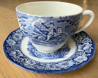 May include: A blue and white porcelain teacup and saucer set with a floral pattern. The teacup features a scene of a cottage and a figure in a field.