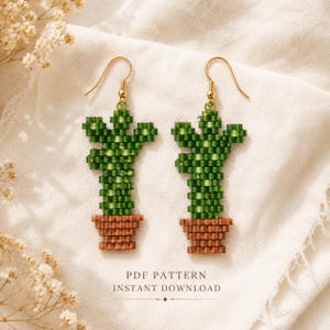 May include: A pair of dangle earrings crafted from small green and brown beads in the shape of a potted cactus. The earrings feature gold-toned metal hooks. The text PDF PATTERN INSTANT DOWNLOAD is printed at the bottom of the image.