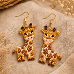 May include: Handmade giraffe earrings. The earrings are made with yellow, brown, and white beads, creating a detailed giraffe design. The giraffe's spots and features are carefully crafted, and the earrings have gold-coloured hooks.