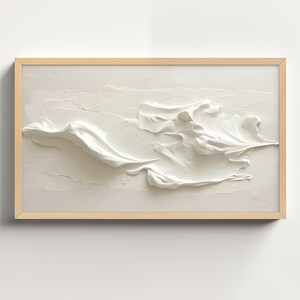 Könnte beinhalten: Ein gerahmtes abstraktes Gemälde mit einem weißen, strukturierten 3D-Design. Das Design ähnelt einer Welle oder einer Wolke.